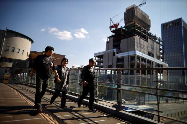 Workers walk past a construction site in Seoul. (REUTERS)