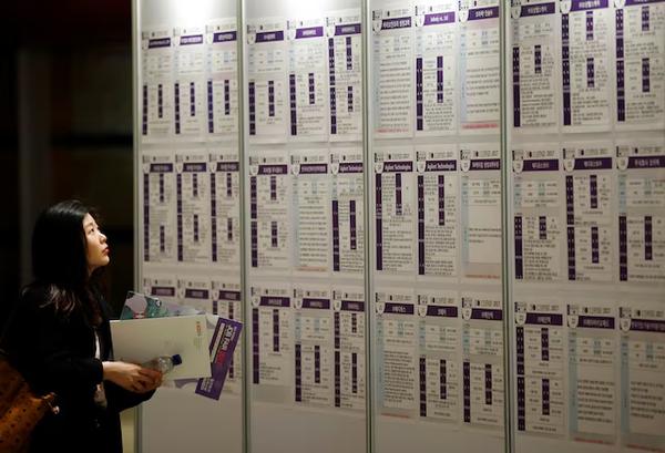 A woman looks at recruiting information during a job fair in Seoul. (REUTERS)