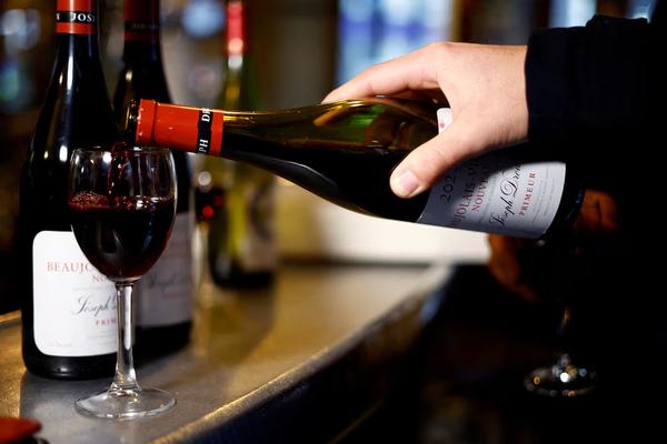 A customer pours a glass of Beaujolais Nouveau wine at Le Mesturet restaurant in Paris, France, Nov. 16, 2023. REUTERS